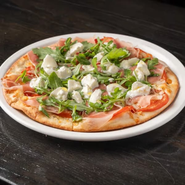 Gabagool Wine Bar's pizza with prosciutto, arugula, fresh mozzarella, and sliced tomatoes on a white plate.