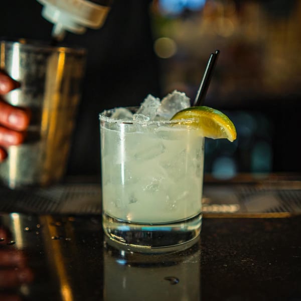 A bartender prepares a Gabagool Wine Bar cocktail, featuring a margarita with a lime wedge.